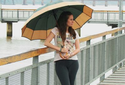 Young woman holding umbrella standing in water