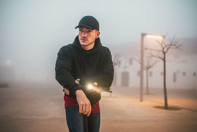 Man with cap on electric scooter during a foggy day