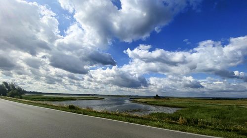 Road amidst field against sky