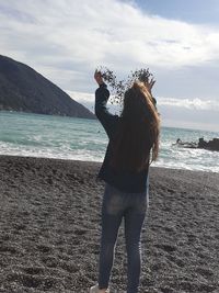 Rear view of woman standing by sea against sky