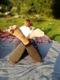 Woman with legs crossed lying on blanket in park