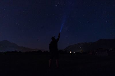 Silhouette person standing on field against sky at night