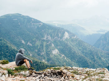 Man sitting on rock looking at mountains