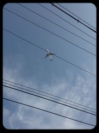 Low angle view of power cables against cloudy sky