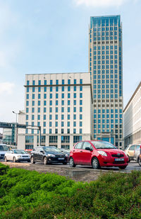 Cars on road by buildings against sky in city
