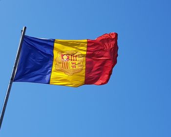 Low angle view of flag against clear blue sky