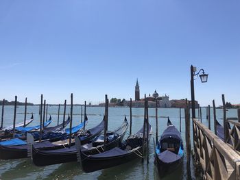 Boats moored in canal against blue sky