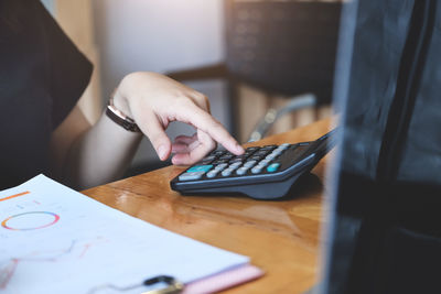 Midsection of woman using smart phone on table