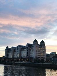 River by buildings against sky at sunset