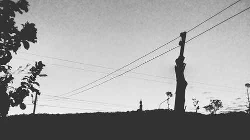 Low angle view of silhouette electricity pylon against sky