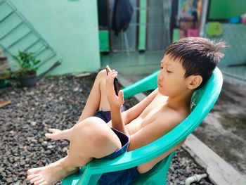 Side view of boy sitting outdoors