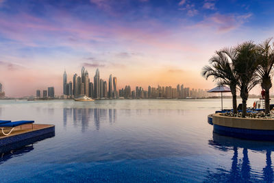 View of swimming pool and buildings against sky during sunset