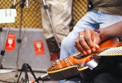 Midsection of man playing guitar