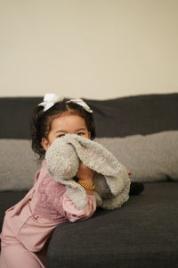 Cute girl holding toy on sofa at home