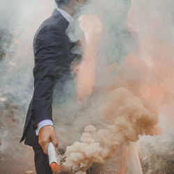 Man holding distress flare while kissing bride