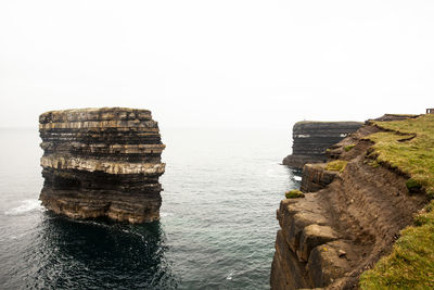 Rock formation in sea against clear sky