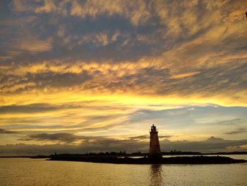 Silhouette tower by river against sky during sunset