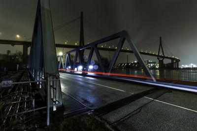 Illuminated bridge over river against sky in city at night