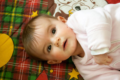 Close-up portrait of cute baby lying on bed