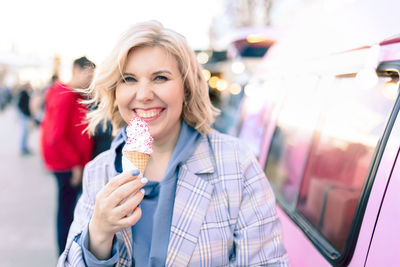 Portrait of smiling woman eating ice cream outdoors