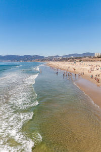 Crowd at beach against clear blue sky