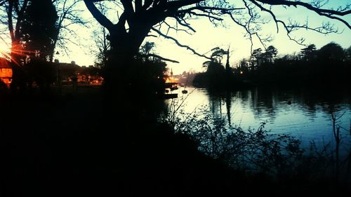 Silhouette trees by lake against sky during sunset