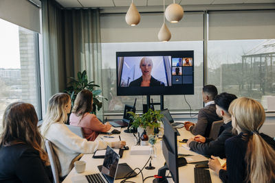 Businesswoman during virtual meeting with male and female colleagues at office