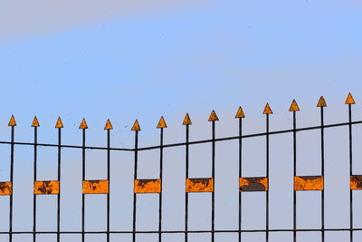 Low angle view of fence against clear blue sky