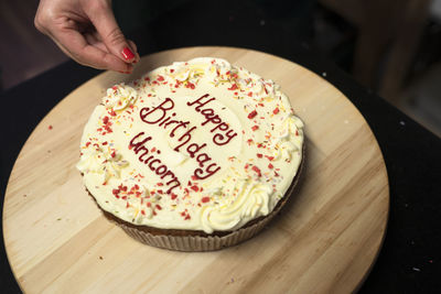 Midsection of person making birthday cake on table