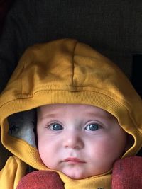 Close-up portrait of baby boy wearing yellow hood