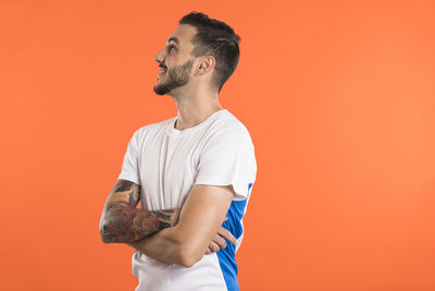 Side view of young man standing against yellow background