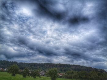 Scenic view of trees against cloudy sky