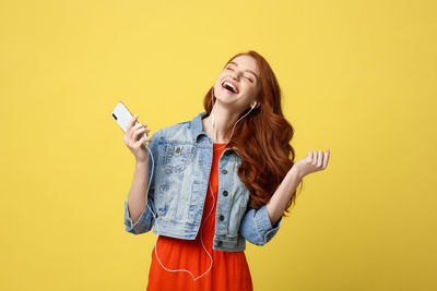 Young woman smiling against yellow background