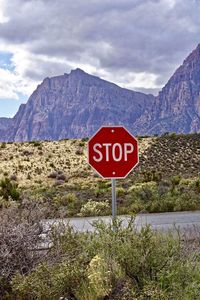 Road sign by mountains against sky