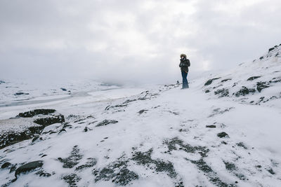 Man standing on snowcapped mountain against sky