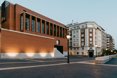 Empty street by buildings against clear sky