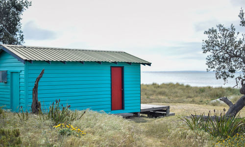 Log cabin on field near sea against sky