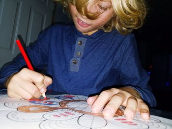 Close-up of boy drawing on paper at table in home