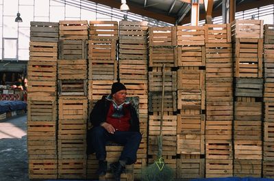 Full length of man sitting on stack of building