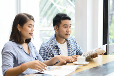 Young couple looking away while sitting on table