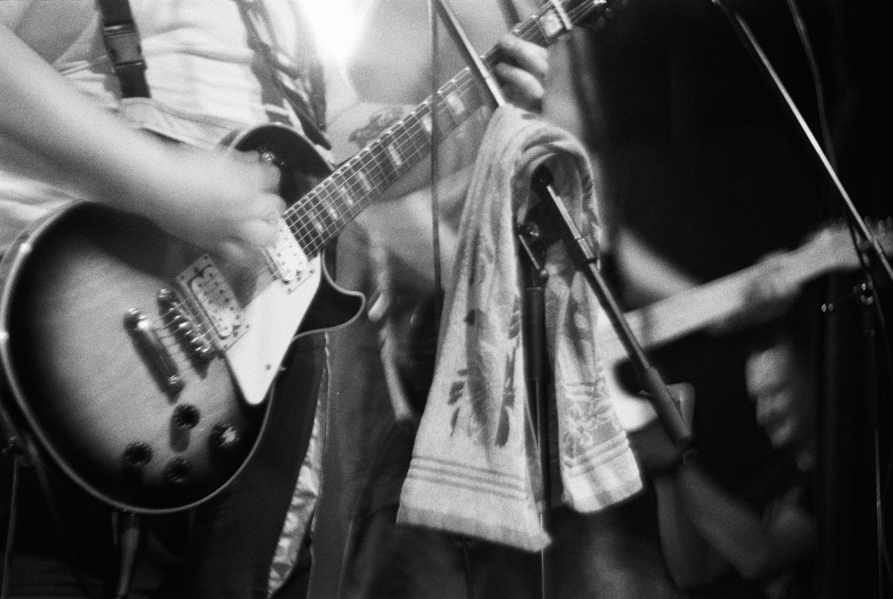 MIDSECTION OF MAN PLAYING GUITAR AT CONCERT