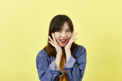 Portrait of smiling young woman against yellow background