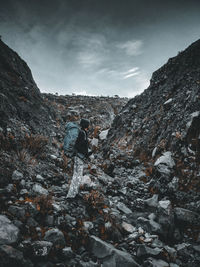 Man on rocks by mountains against sky