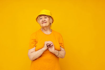 Portrait of young woman against yellow background