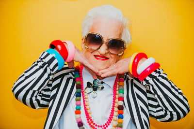 Portrait of woman wearing sunglasses against yellow background