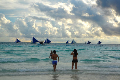 Rear view of people on beach against sky