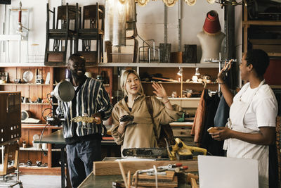 Female entrepreneur waving hand to customers in upcycling store