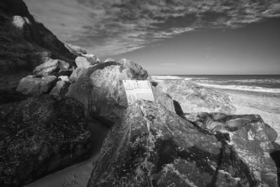 Rock formation on beach against sky