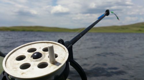 Close-up of coin-operated binoculars by sea against sky