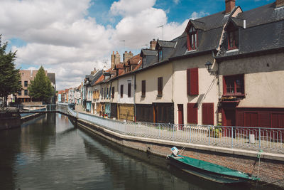 Boats in canal amidst buildings against sky